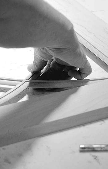 An American cabinet maker crafting the details of a mullion cabinet door in a black and white photograph.