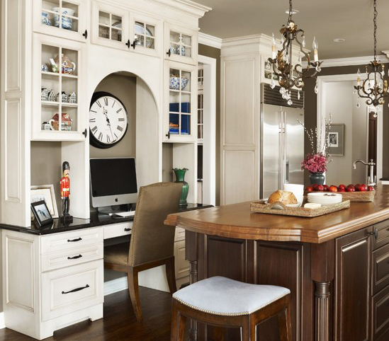 A traditional style kitchen with a built-in kitchen office desk with an arched detail and decorative glass cabinet storage.