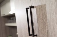 A close up of slab cabinet doors with a textured foil material in a light gray with a straight grain pattern.