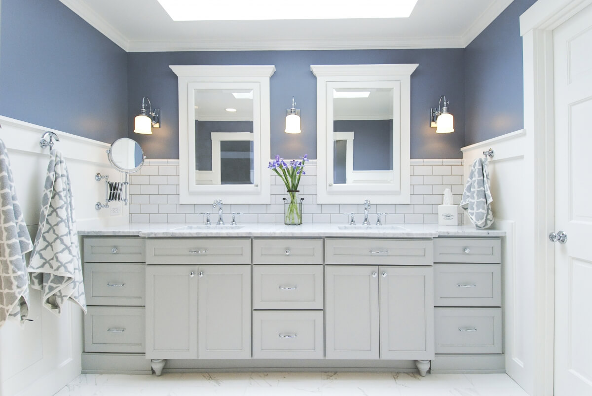 A cool gray painted master bathroom vanity with white subway tiles and blue painted walls.