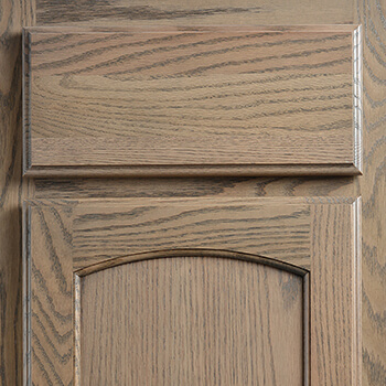 Standard overlay cabinet door construction with a stained oak wood cabinet. A Standard (or Partial) Overlay door overlaps the face frame by 3/8” and leaves a reveal of 1 1/8” of the face frame exposed on all sides (left, right, top & bottom).