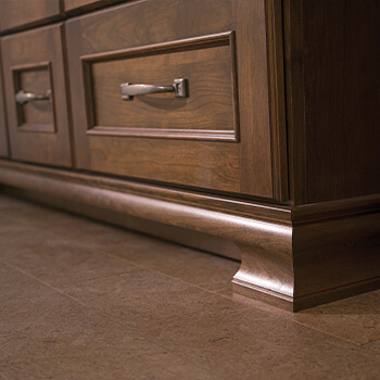 The detailed modling at the bottom of a furniture style vanity. The bathroom vanity cabinets are crafted by Dura Supreme Cabinetry.