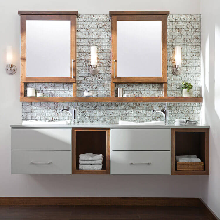 A two-toned floating vanity with light gray paint and warm stained wood with open storage and a floating shelf connecting to the dual medicine cabinets with a modern design.