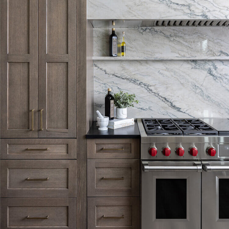 A beautiful kitchen design with medium, true-brown stained quartersawn white oak cabinets paired with a quartz backsplash and hood.