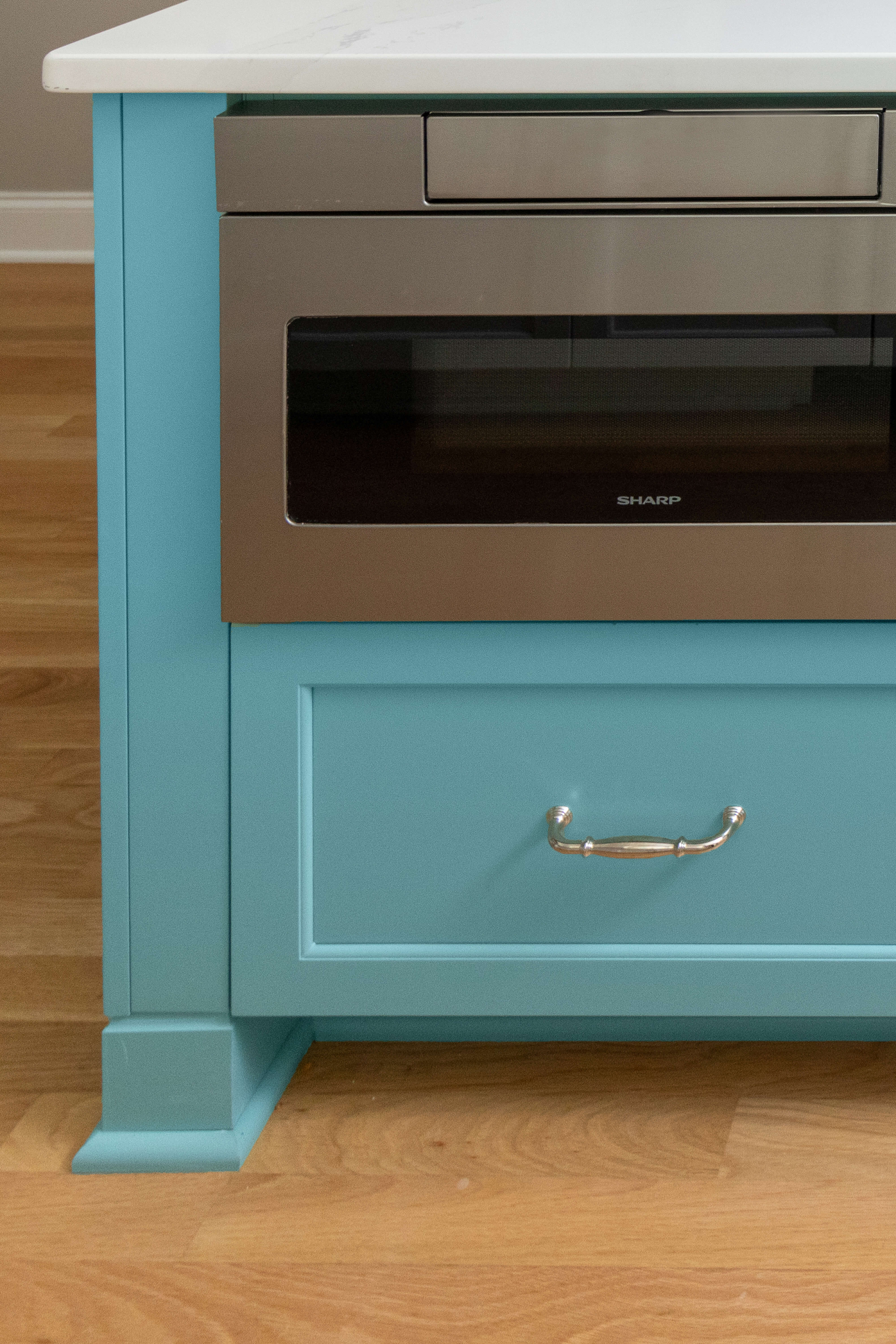 A light blue painted kitchen island with furniture style feet and styled toe space.