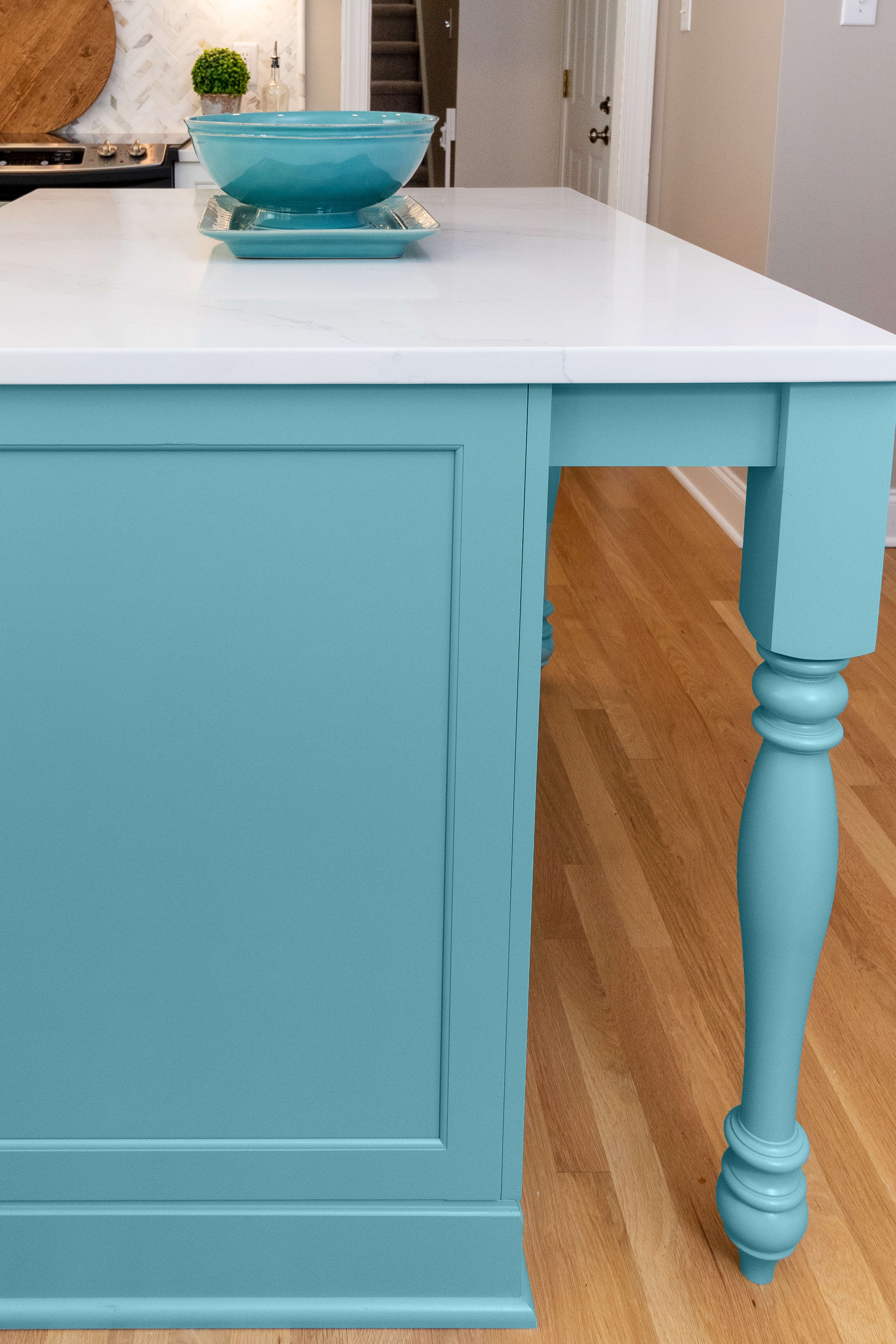 A sky blue kitchen island with turned post table legs. Painted kitchen island cabinets from Dura Supreme Cabinetry.