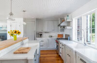 A gray and white cottage style kitchen with inset cabinets that have a beaded panel within the cabinet doors.