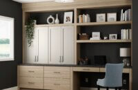 The Dura Supreme office cabinets and built-in desk feature a combination of a slab door style in light stain on the Hickory wood cabinets paired with a detailed flat panel door style in a natural off-white painted finish. This built-in desk and office cabinets were customized to fit the homeowners needs for working from home.