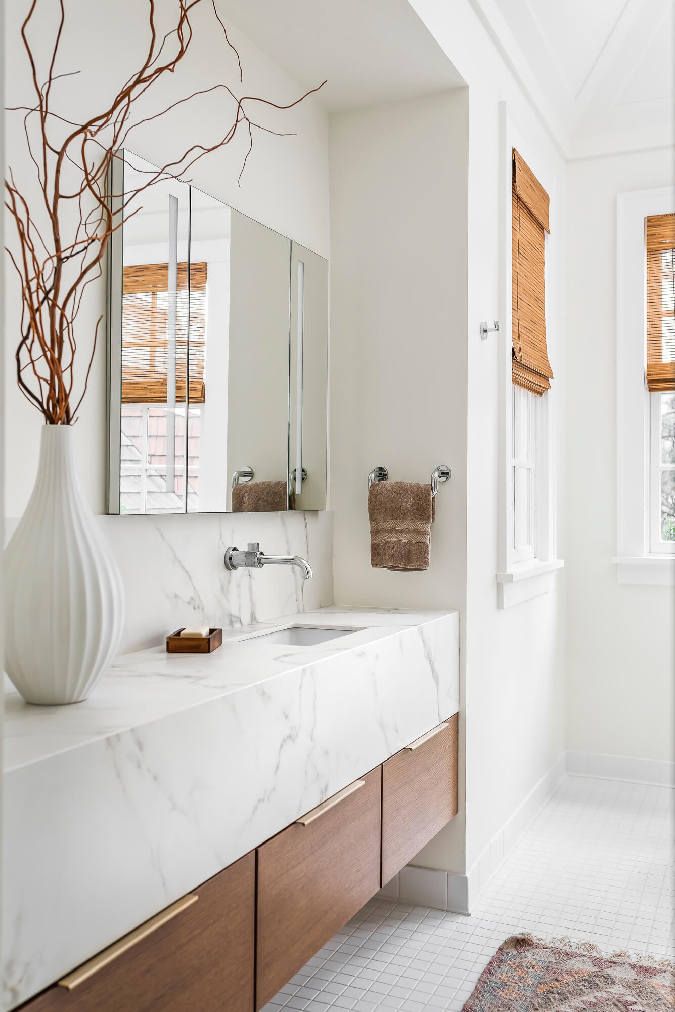 An elegant floating bathroom vanity with two deep drawers and a very think and tall vanity countertop in a white quartz material. The inset in the wall framed the vanity and mirror.
