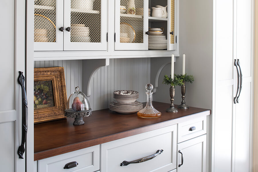 A traditional, old English style kitchen design with light gray/off-white cabinets in a mix of inset and full overlay.