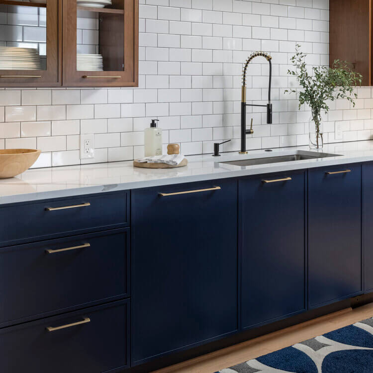 A modern kitchen with skinny shaker cabinet doors in a navy blue paint and a warm stained cherry wood.