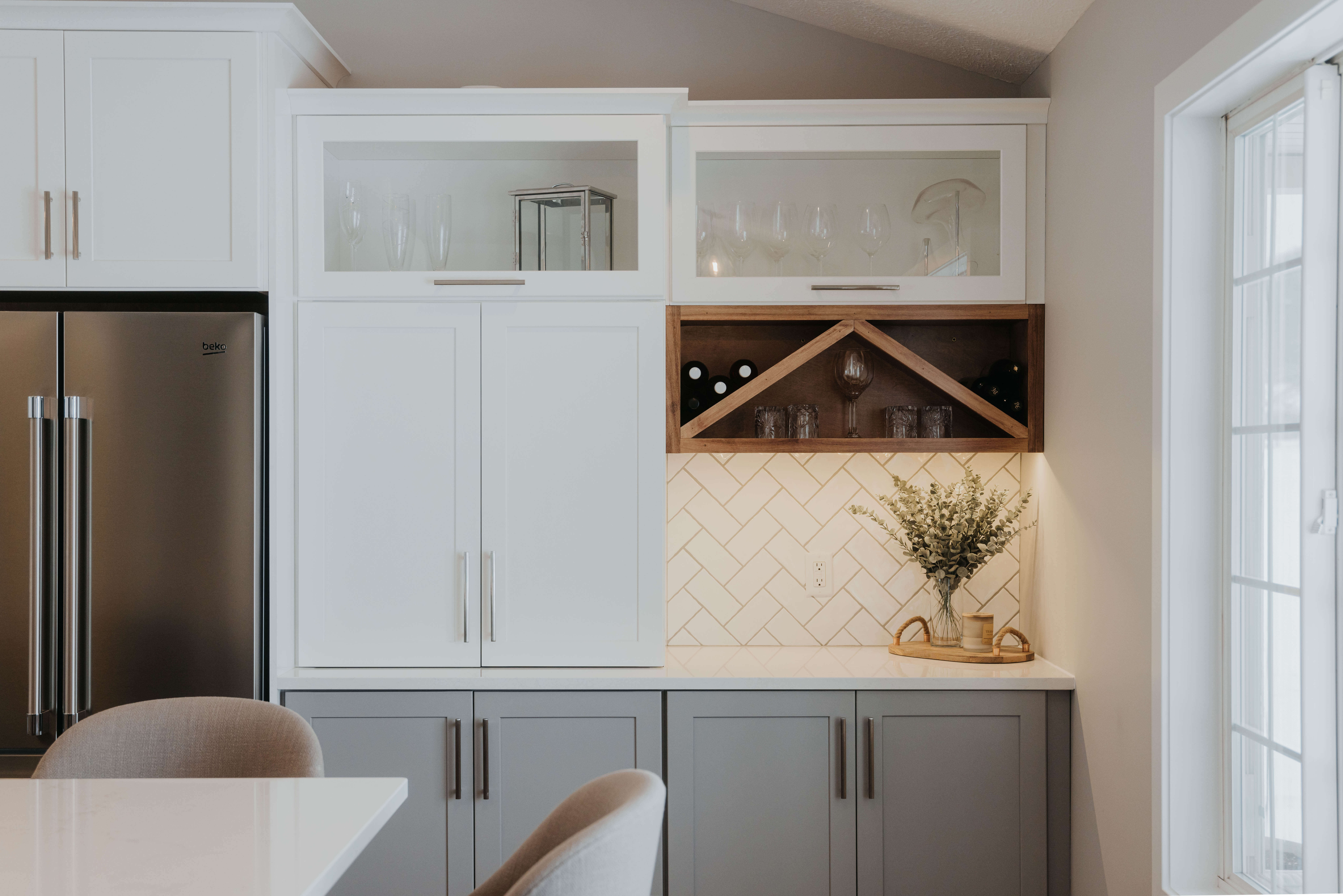 An open shelf in this kitchen uses a contrasting stained wood finish and slanted selves to create a unique focal point and beautiful storage for wine bottles.