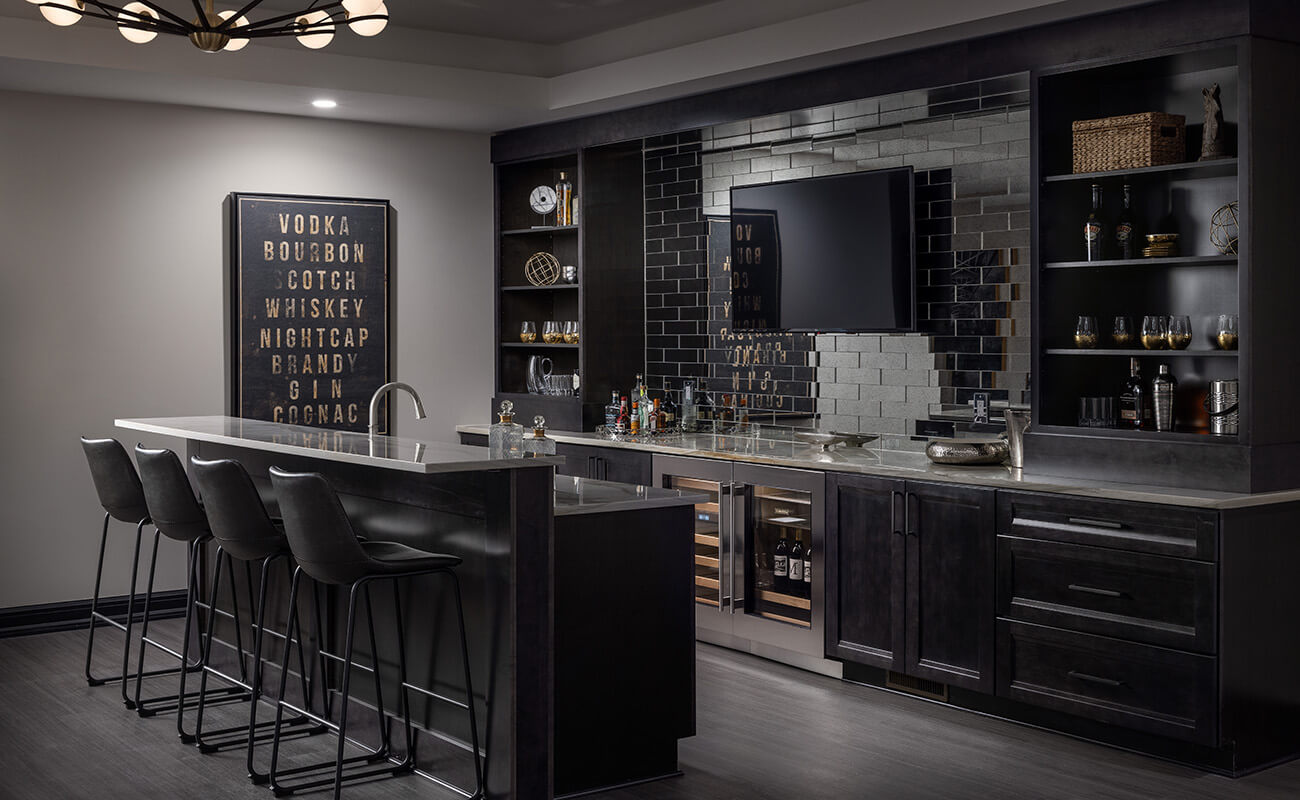 A home bar and entertainment room with dramatic black painted cabinets with custom storage.