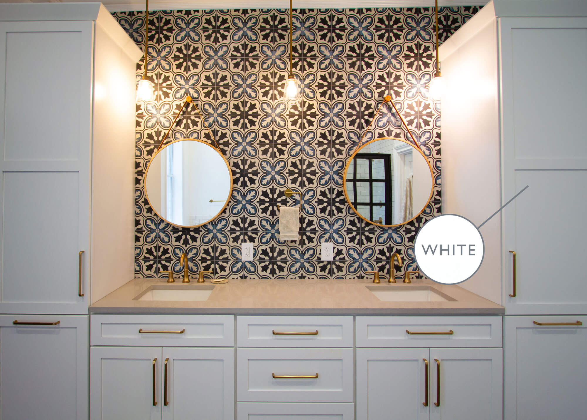 A bathroom vanity in dim lighting with white painted cabinets.