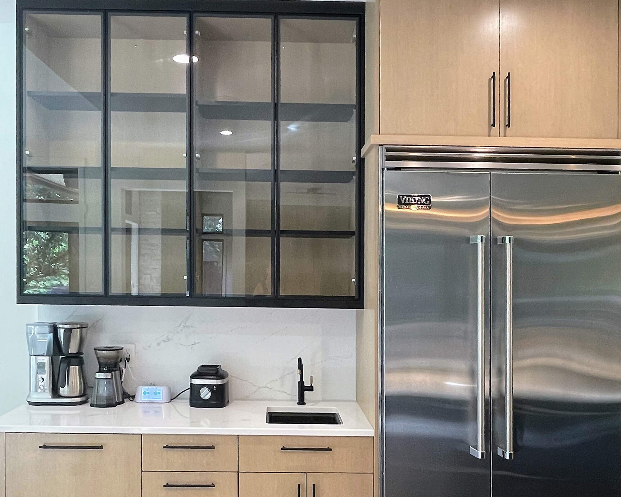 An industrial style kitchen with black metal framed cabinet doors with plain glass inserts.