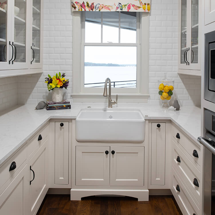 An all white butler's pantry design with an apron sink in the middle.