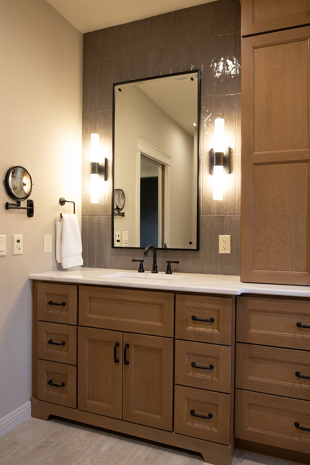 A furniture styled vanity with a linen cabinet tower to the right with a furniture like style.