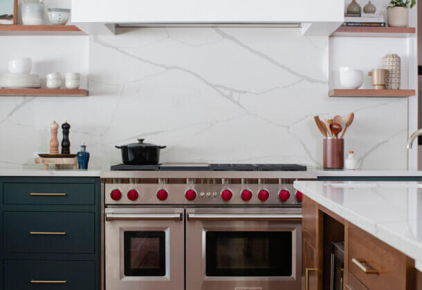 This kitchen is a great example of the latest trend of deep, earthy green cabinetry. Green is the color of nature, and it symbolizes growth, harmony, freshness, and fertility. This kitchen showcases Dura Supreme Cabinetry with the Homestead Panel Inset door style with optional solid slab drawer fronts in a combination of the “Rock Bottom” painted finish (perimeter cabinets) and the “Toast” stain on Cherry (kitchen island & floating shelves).