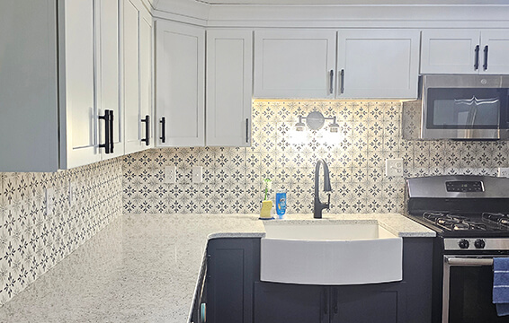A two-tone kitchen remodel with white painted cabinets on the top and dark, navy blue cabinets on the bottom featuring a customer testimonial on Dura Supreme cabinets.