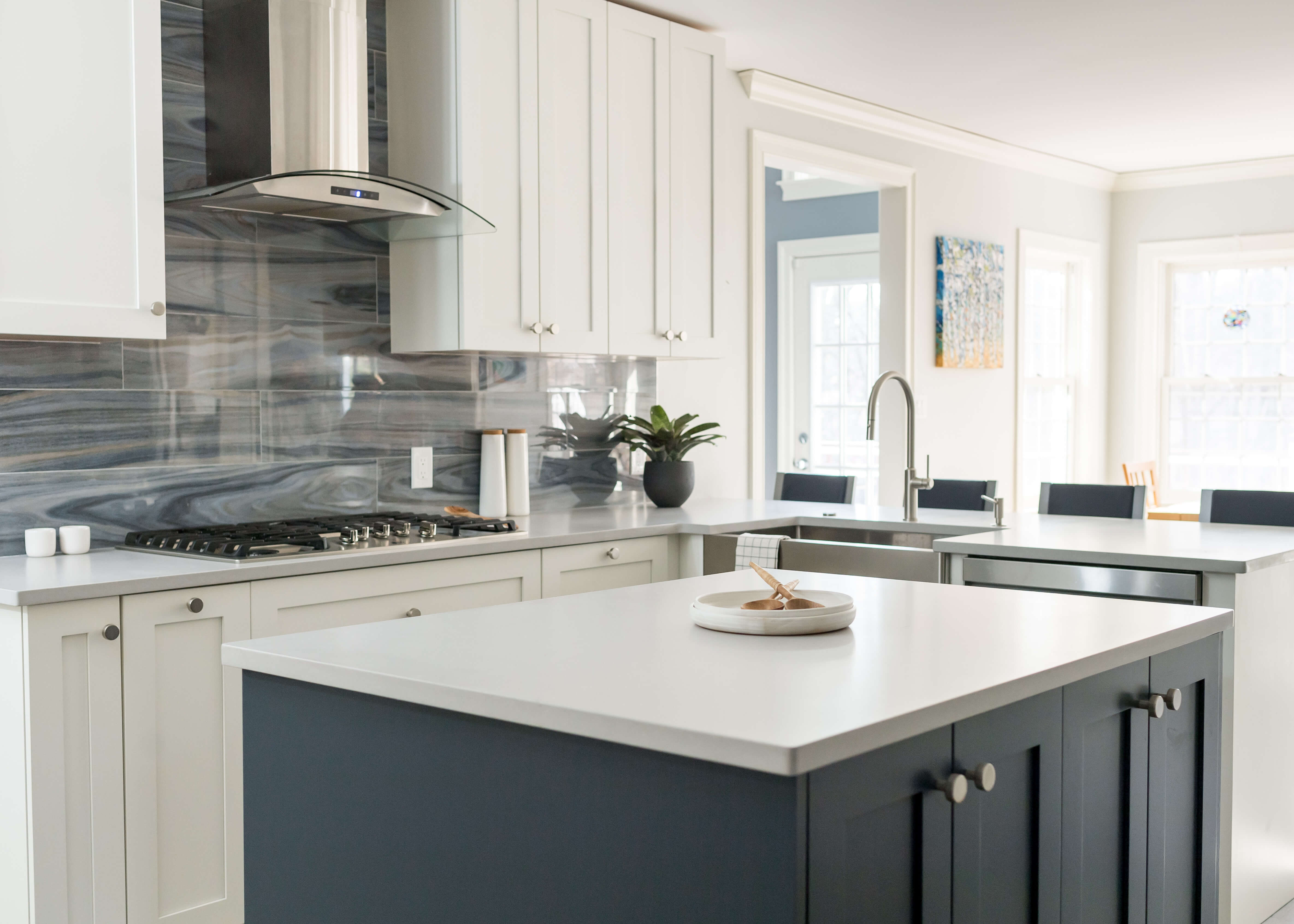 Two-tone kitchen cabinets pair bright white painted perimeter cabinetry with a dark gray painted kitchen island for timeless contrast. A mix of round cabinet knobs and sleek modern pulls adds designer-inspired detail to this bright, open kitchen.