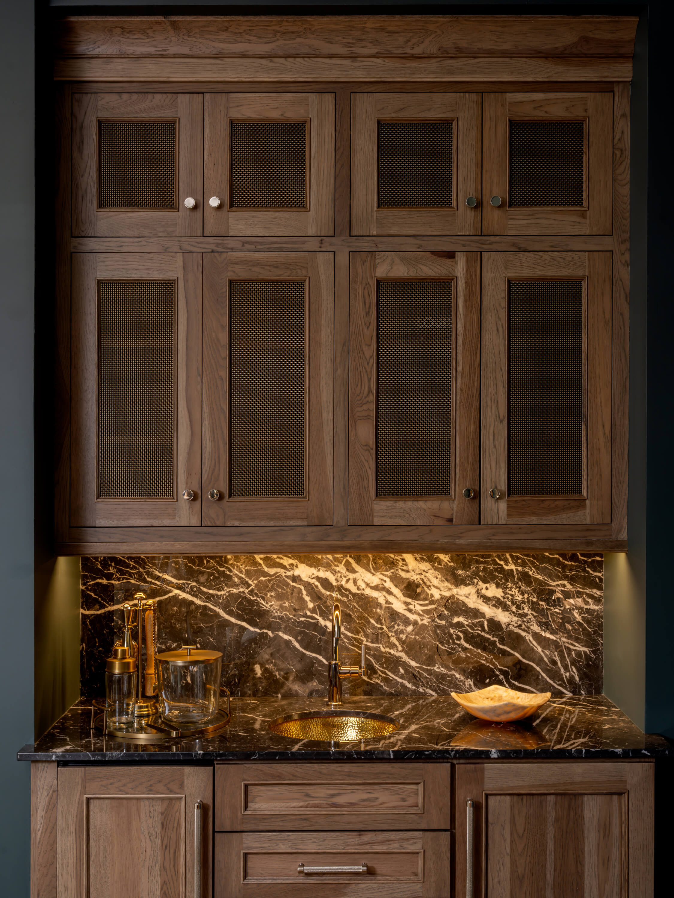 These custom kitchen cabinets feature wire mesh cabinet door inserts in an antique brass that add texture and visual interest to the upper cabinetry. The decorative mesh panels complement the warm wood finish while providing a distinctive artisan-inspired design detail.